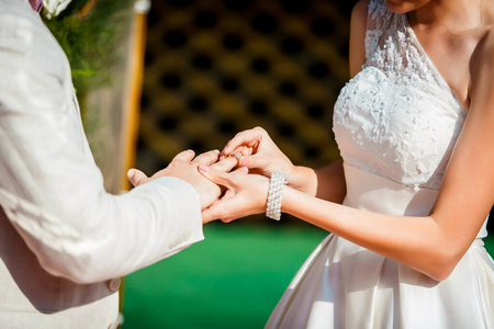 婚礼上，新娘把结婚戒指戴在新郎的手上。新婚夫妇
