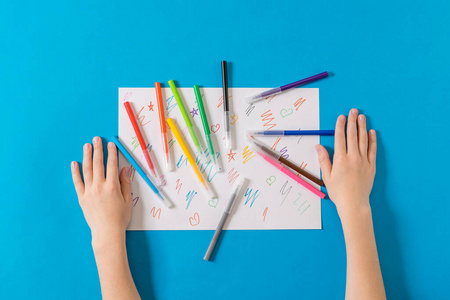 孩子们的手上有一套记号笔和一张蓝色背景的纸。