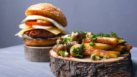 fried potatoes with mushrooms and a juicy burger on forest woode