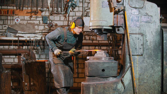 锻造工业一个把热金属片置于大机器压力下的铁匠