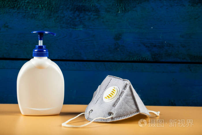 蓝色现代口罩白色消毒液容器隔离在橙色背景上