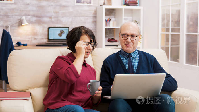 戴着眼镜的爷爷奶奶坐在沙发上和家人聊天