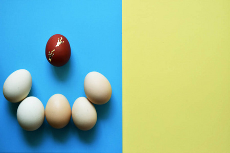 白色复活节彩蛋，蓝色和黄色背景，一个红色彩蛋。