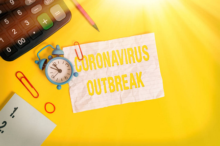 显示冠状病毒爆发的文字标志。概念图片传染病引起的新发现COVID19闹钟夹注橡皮筋计算器铅笔色背景。