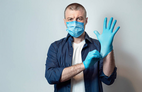 灰色的橡胶防护手套成熟男子戴口罩戴防护手套,灰色背景照片