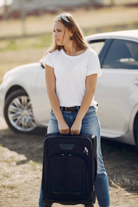 Elegant woman by the car with a suitcase