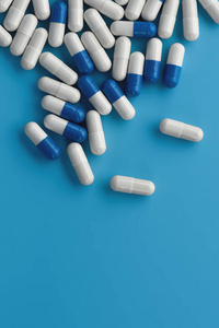 Blue and white medicine capsules on blue background with copy sp