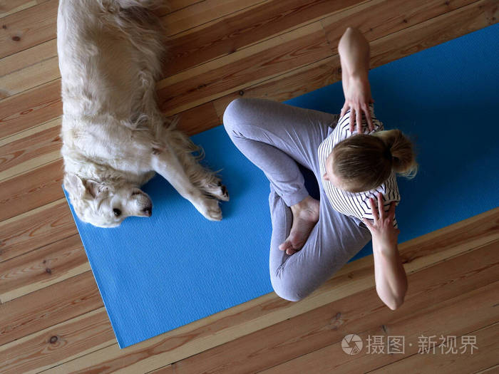 呆在家里。隔离期间，一名妇女在客厅做瑜伽，附近躺着一只大狗。