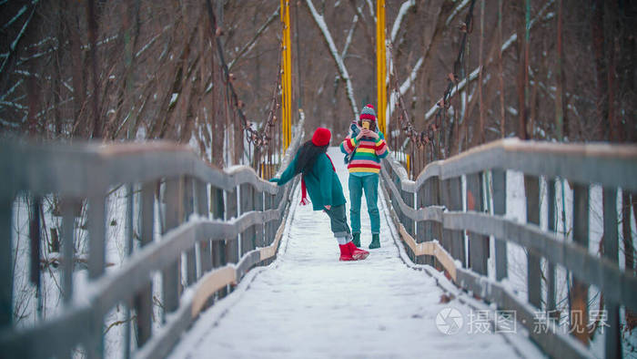 两位五彩缤纷的女子在雪桥上拍照