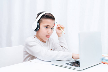  Child study online sitting on the a computer with headphones. C