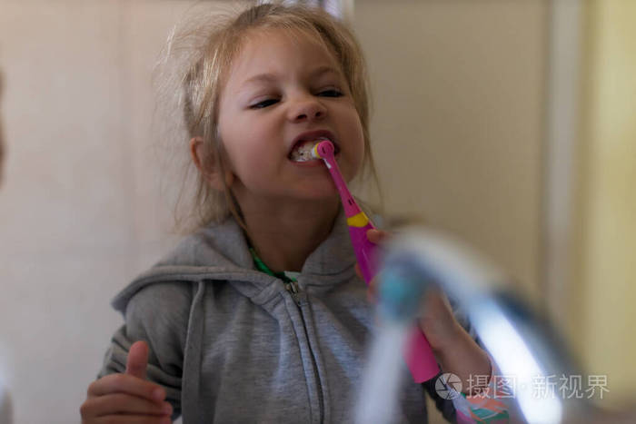 Emotional close up of a cute little girl brushing teeth with ele