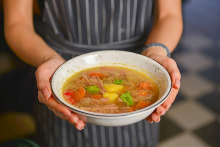 端汤一个穿着黑色制服的服务生在餐馆里端一碗热汤.