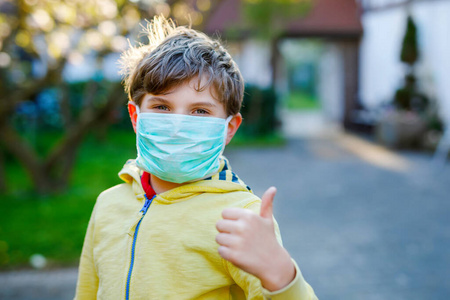 可爱的小男孩戴着医用面具，以防大流行性冠状病毒检疫性疾病。学龄儿童使用防护设备对抗covid19。