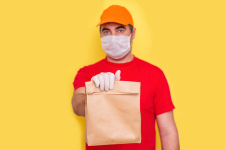 A courier employee in uniform holds a cardboard box with food is