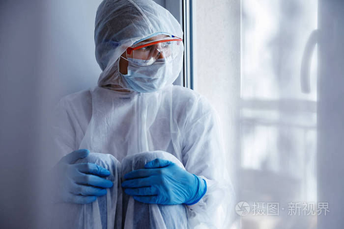 孤独隔离年轻女子戴着医用面罩望向窗外自我隔离冠状病毒大流行概念