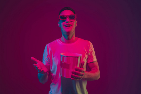 白种男人的肖像孤立在粉紫色的霓虹灯背景下，戴着3D电影眼镜