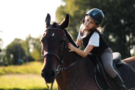 少女骑师坐在一匹棕色的马上,拥抱和抚摸她.照片