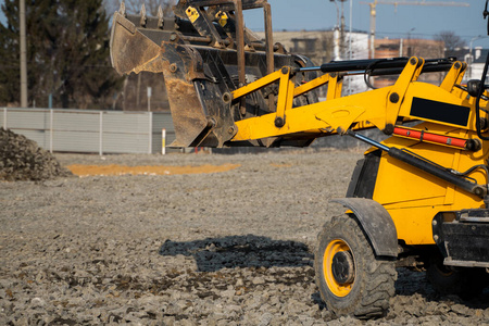 黄色轮式装载机在施工现场用砂石挖掘机工作。准备沥青的基础。道路施工现场。建造停车场。