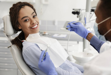 漂亮的黑人妇女坐在牙医椅上准备检查