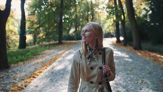 秋天，美丽的金发女孩在公园散步