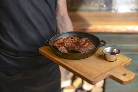 侍者拿着盘子和烤肉放在锅里。烧烤用的辛辣烤肉。餐厅里穿着制服的服务员。