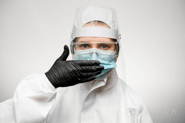 身穿医用防护服的妇女用手捂住嘴戴着黑色乳胶手套