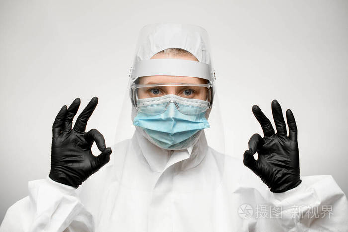 身穿医用防护服和黑色乳胶手套的女士举手示意可以