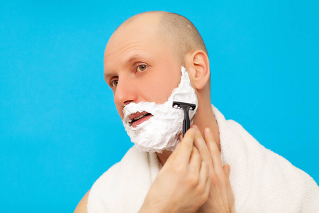 浴室里的男人用剃须刀刮胡子照片