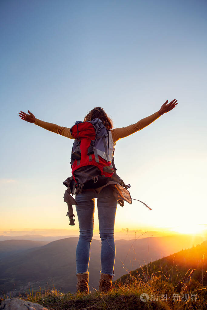 欢呼雀跃的女徒步旅行者在山顶张开双臂