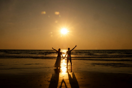 一对度假情侣在夕阳下漫步在海滩上相爱照片