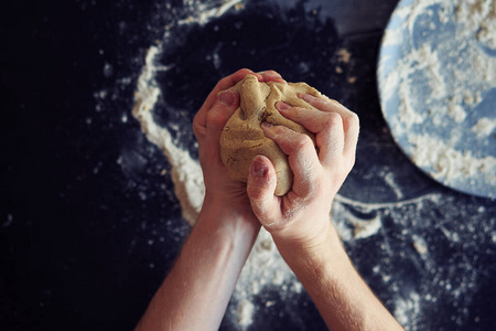  Unrecognizable male cook crumples the dough, closeup