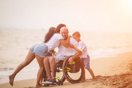 残疾人坐在轮椅上和家人在海滩上。