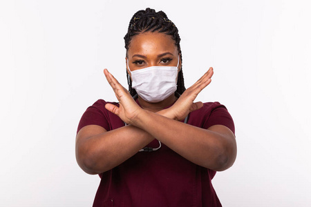 医生在白色背景下双手交叉放在胸前.他戴着医用面罩.禁止或停止手势.