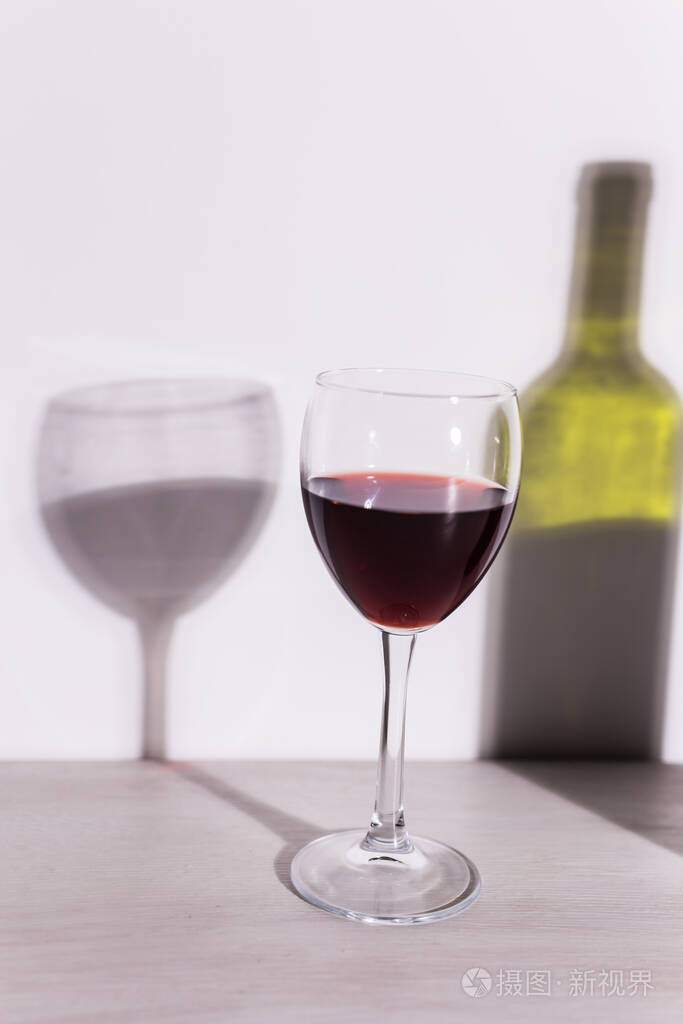 一杯酒和一瓶酒在夕阳下投下长长的影子