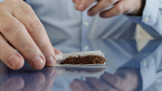 吸烟者用香烟纸,滤嘴和烟草卷一支手工制作的香烟照片