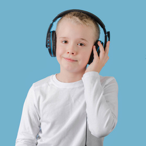 小孩子把手放在耳机上听音乐。戴着耳机看着摄像机的男生