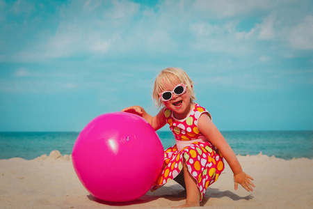 可爱的小女孩在热带海滩上玩球
