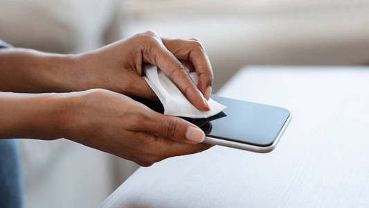 白色工作室背景,不规则剪裁,不知名女士在为智能手机消毒女人给手机