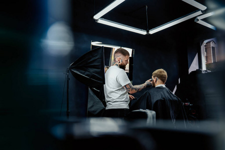 男性用电动剃须刀理发。纹身理发师在理发店用理发器为顾客理发。男人用电动剃须刀理发。