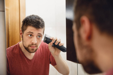 A man cuts his hair on his head with an electric razor 