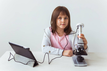 女学生在科学课上使用显微镜。技术课程和儿童概念。