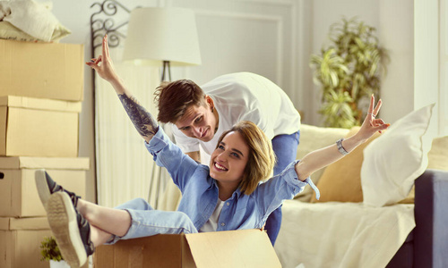 一对幸福的夫妇在新家里玩得开心，坐在纸板箱里
