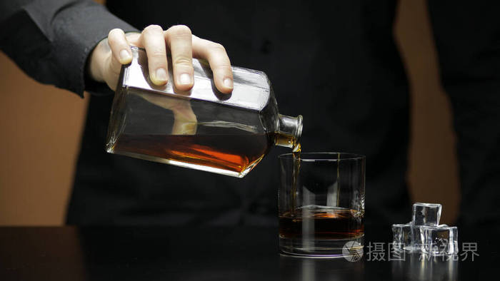 把威士忌白兰地倒进玻璃杯里酒保倒酒轮廓