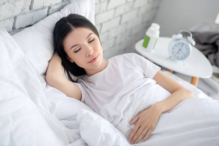 平静安详黑发女子安详地睡在床上,一只手枕着头照片