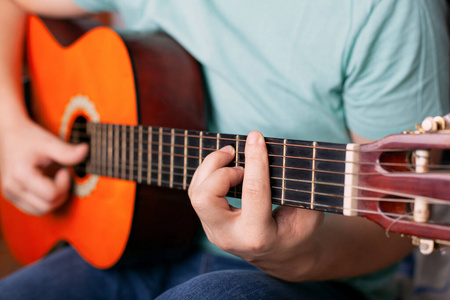 一个人弹原声吉他，一个手指握着一个酒吧和弦。学会演奏乐器