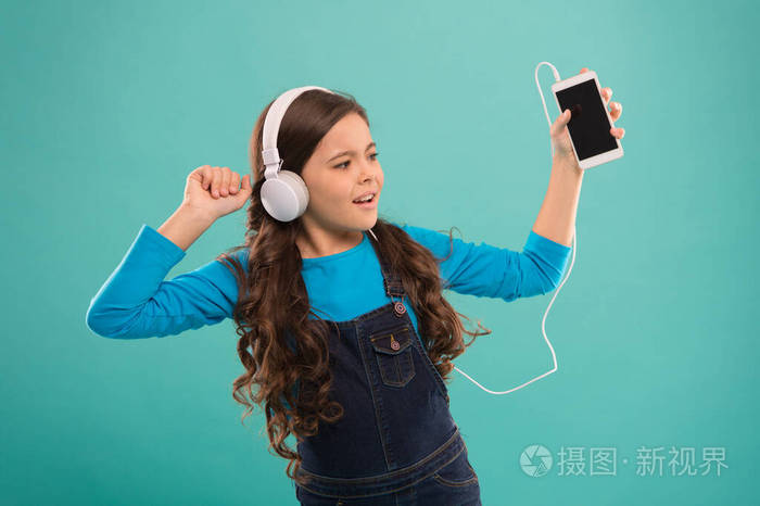 小女孩戴着耳机听音乐在智能手机播放列表中选择曲目mp3播放器孩子们