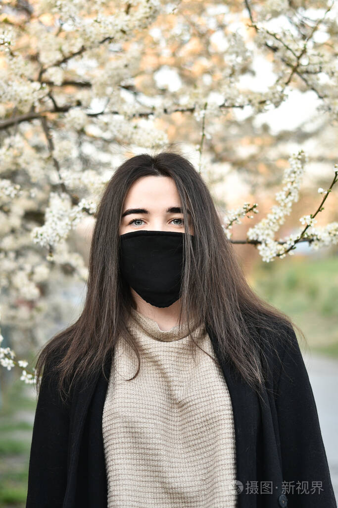 戴着医用口罩和手套的女孩花背景是covid19春天的白色