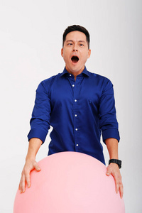 一个男人拿着大粉红球摆姿势的摄影棚肖像