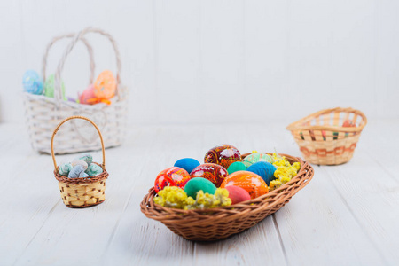 彩色复活节彩蛋放在白色木制背景的篮子里