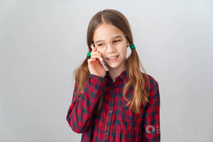 白墙附近的可爱女孩在手机旁聊天